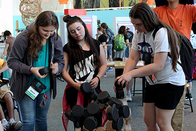 Phase I Scholars Emma and Hayley try out a hands-on Pacific Science Center exhibit with Intern, Brookelyn.