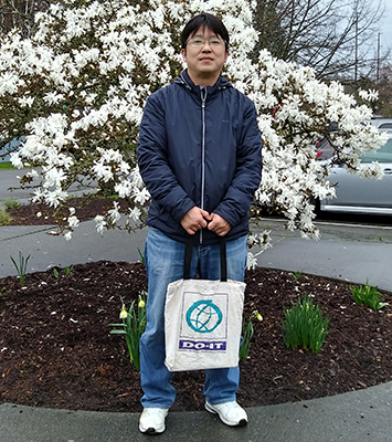 Jungsoo Kim smiles at the camera, with a background of flowers.