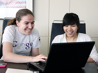 Photo of two women working on a project together using a computer