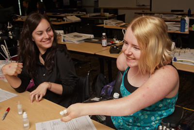 Photo of DO-IT Scholars McKenna and Kayla laughing while working on a science project during Summer Study 2013