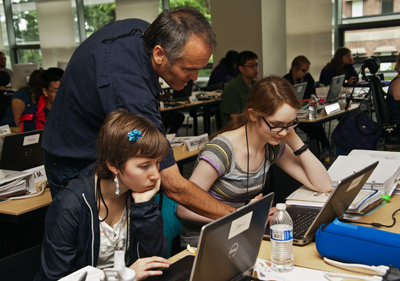 Photo of DO-IT staffer Doug works with Phase I Scholars Ellen and Hannah with something on their laptops during Summer Study 2013