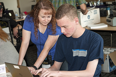 An instructor shows a student what to do on the computer.