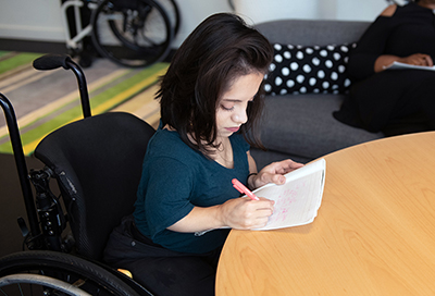 Woman in a wheelchair writing.
