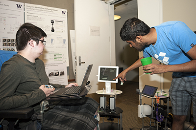 A mentor shows a student how to use a robot.