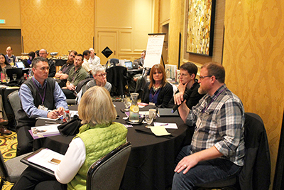 A participant speaks into a microphone from his table.