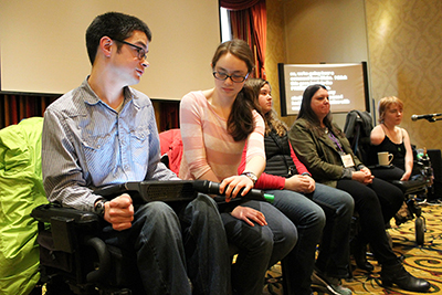 In the students with disabilities panel, Hannah holds the mic to Blake's assistive technology.