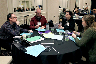 A group of conference participants discuss while sitting at a table.