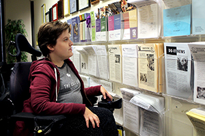 A staff member in a wheelchair looks at publications on the wall.