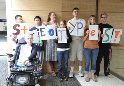 Eight students of different heights and abilities hold up the letters that spell "Stereotypes!"