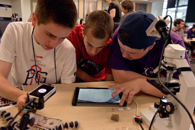 Three students with visual impairments look down at an enlarged screen on a tablet.