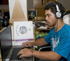 Student at a computer listening to headphones. Photo of a student at a computer listening to headphones.