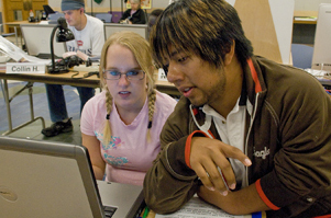 Students gathered around a laptop computer. Photo of student at a laptop computer.