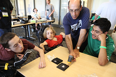 Three participants huddle around a table watching an oceanography experiment demonstrated by a mentor.