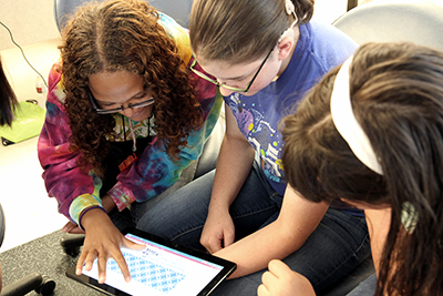 A group of students do an activity on a tablet.