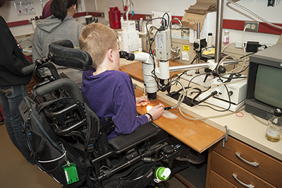 -	Grady, a Phase II Scholar, does an experiment under a microscope during Summer Study 2016.