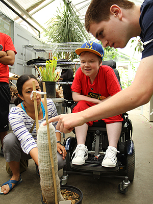 Image of an instructor showing two students a cactus in a botany lab