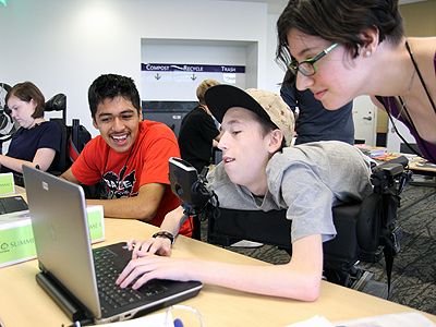 Image of three students looking on a laptop screen together