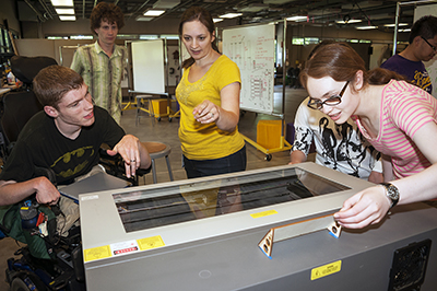 DO-IT Staff Brianna shows 3 students a piece of equipment in the UW CoMotion Makerspace.