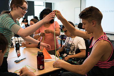 DO-IT Intern Hannah helps Phase I Scholar Dewald with a kite making project.