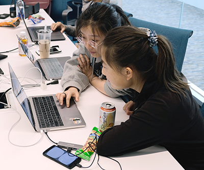 Two students work on a laptop together.