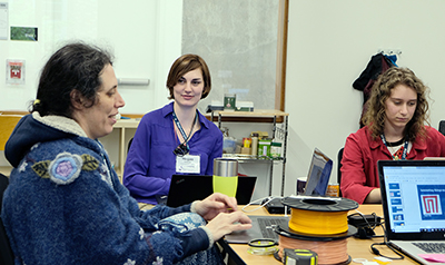 Faculty member Jen Mankoff works on a computer with two students.