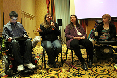 A panel of students with disabilities talk in front of the room. A panel of students with disabilities talk in front of the room.