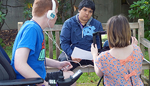 Two students film another student with a script.