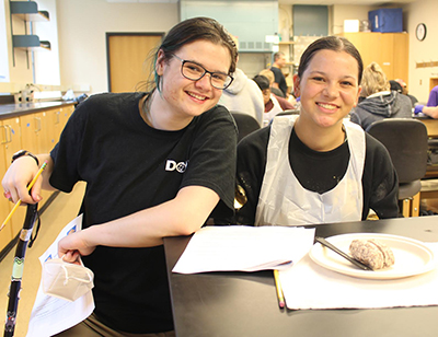 Piper Hawley assists a high school student during the sheep brain dissection lab as part of The DO-IT Center neuroscience camp for neurodiverse learners.