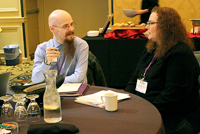 A man and woman talk at a table.