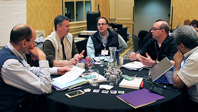 A group of participants speak together around a table.