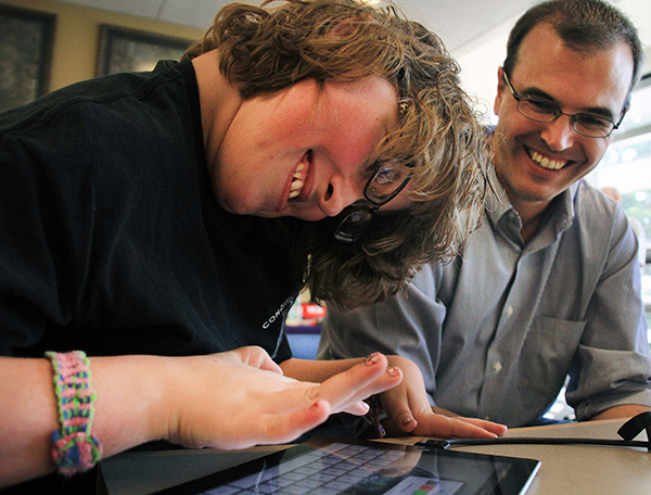 An instructor works with a student on a tablet.