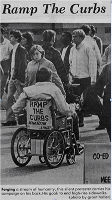 A newspaper clipping showing a man in a wheelchair with "Ramp the Curbs"on the back of his chair A newspaper clipping showing a man in a wheelchair with "Ramp the Curbs"on the back of his chair