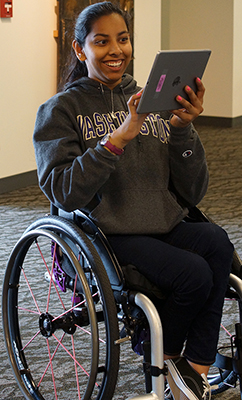 A female student in a wheelchair uses a tablet.