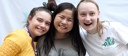 Three students smile at the camera.