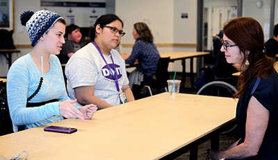 Two students meet with a staff member to practice interviews.