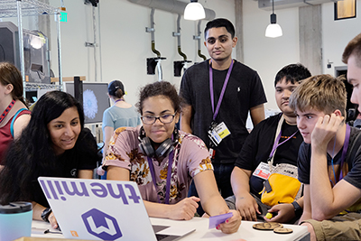 A group of students look at a computer with an instructor.