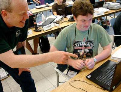 Photo of instructor helping a student on his laptop.