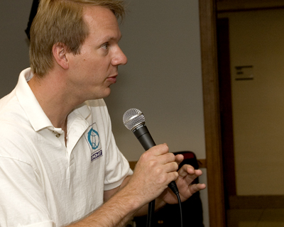 Image of faculty member Scott holding a microphone giving a speech.