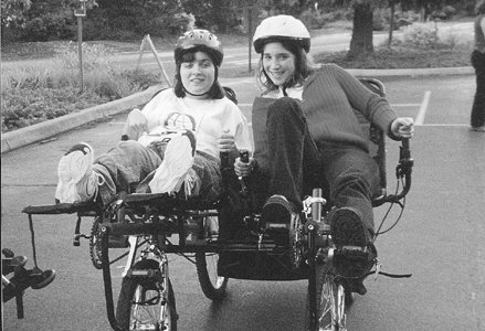 Photo of DO-IT Scholars Corina and Crystal on an adapted bike