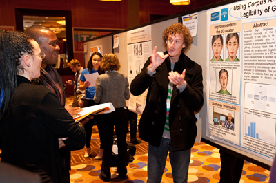 Photo of AccessComputing participant Larwan explains his poster and research at the Tapia Conference.