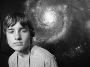 Photo of student in front of large picture of a spiral galaxy