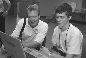 Photo of DO-IT Staff member Scott Bellman looking at a laptop computer screen with a DO-IT Scholar in classroom.