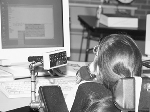 Image of Scholar in a wheelchair uses assistive technology to control her computer mouse using her chin.