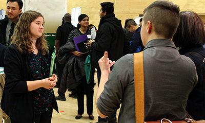 A student talks to someone at a conference with an interpreter.