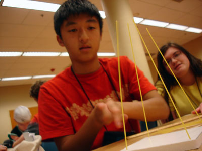 Picture of two students designing a structure using dried spaghetti.