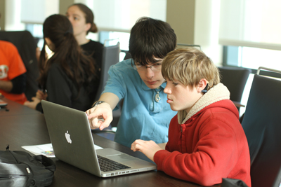 Student working with mentor on laptop.