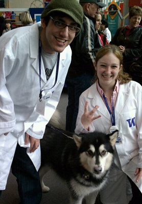 Group photo of DO-IT staff Noah Seidel and Jennifer Gears pose with the UW mascot, Dubs, at Paws on Science. 