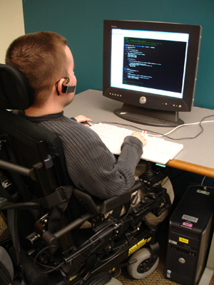 A male student in a wheelchair works with a computer.