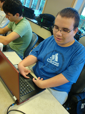 Photo of 2012 Scholar Garrett wearing a blue shirt types on a laptop.