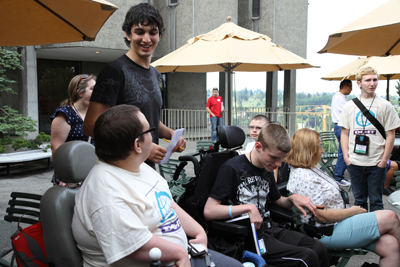 Candid photo of DO-IT Scholars at the 2012 new scholar BBQ. In the forefront are (from right to left) 2012 Scholars Eric, Ryan, and Garrett, who is talking to his PCA.